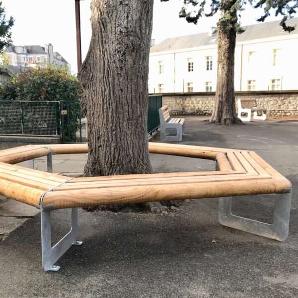 Banc tour d'arbre bois / métal. Banc en bois et en métal parfait pour une cour d’école. Son envergure permet l'installation autour d'un arbre de belle circonférence (sur la photo l'arbre fait 0,90 cm de diamètre). Le banc est conçu avec des angles arrondis pour plus de sécurité et de confort. Son bois chaleureux et ses solides profils en acier de 8 mm offrent au banc une robustesse à tout épreuve. Son design ludique et épuré s’accompagne d’une finition galvanisée pour une allure contemporaine, complétée éventuellement d’une peinture poudre pour une allure plus fun et ludique. Livré en 3 côtés montés (avec rondins et lattes des 3 autres côtés en attente) pour installation sur place.