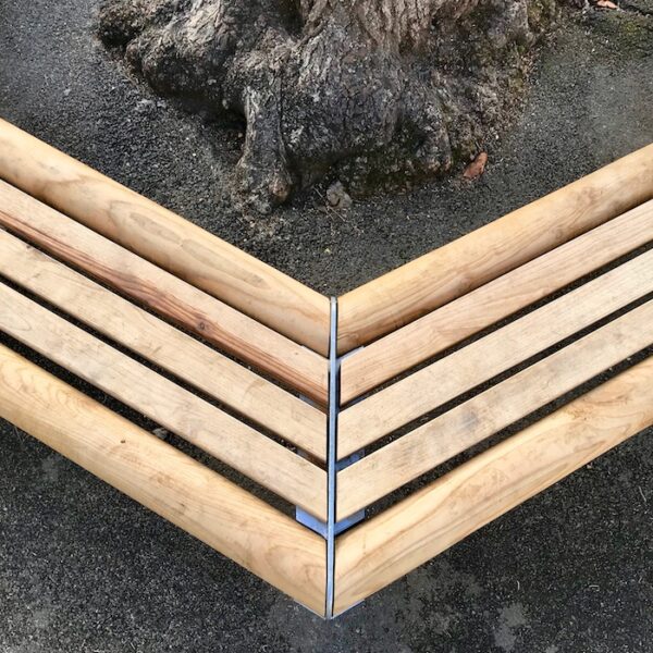 Banc tour d'arbre bois / métal. Banc en bois et en métal parfait pour une cour d’école. Son envergure permet l'installation autour d'un arbre de belle circonférence (sur la photo l'arbre fait 0,90 cm de diamètre). Le banc est conçu avec des angles arrondis pour plus de sécurité et de confort. Son bois chaleureux et ses solides profils en acier de 8 mm offrent au banc une robustesse à tout épreuve. Son design ludique et épuré s’accompagne d’une finition galvanisée pour une allure contemporaine, complétée éventuellement d’une peinture poudre pour une allure plus fun et ludique. Livré en 3 côtés montés (avec rondins et lattes des 3 autres côtés en attente) pour installation sur place.