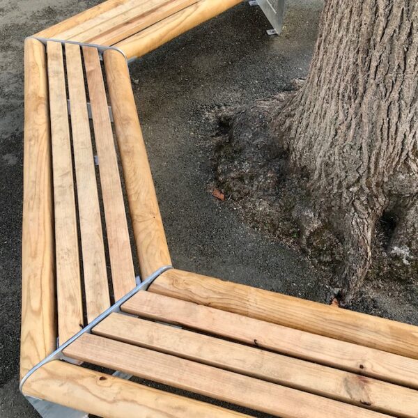 Banc tour d'arbre bois / métal. Banc en bois et en métal parfait pour une cour d’école. Son envergure permet l'installation autour d'un arbre de belle circonférence (sur la photo l'arbre fait 0,90 cm de diamètre). Le banc est conçu avec des angles arrondis pour plus de sécurité et de confort. Son bois chaleureux et ses solides profils en acier de 8 mm offrent au banc une robustesse à tout épreuve. Son design ludique et épuré s’accompagne d’une finition galvanisée pour une allure contemporaine, complétée éventuellement d’une peinture poudre pour une allure plus fun et ludique. Livré en 3 côtés montés (avec rondins et lattes des 3 autres côtés en attente) pour installation sur place.